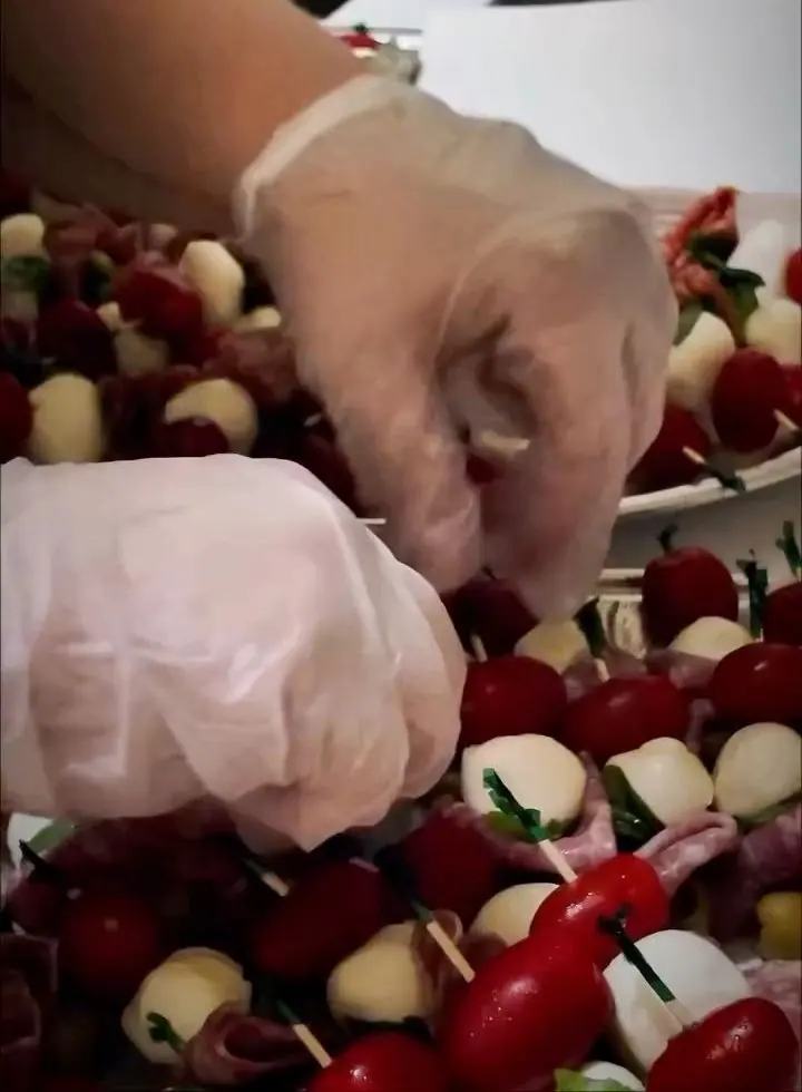 Gloved hands setting caprese skewers onto a platter