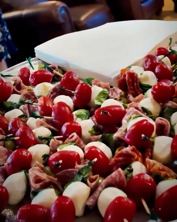 A platter of caprese skewers: cherry tomatoes, bocconcini, basil and salami