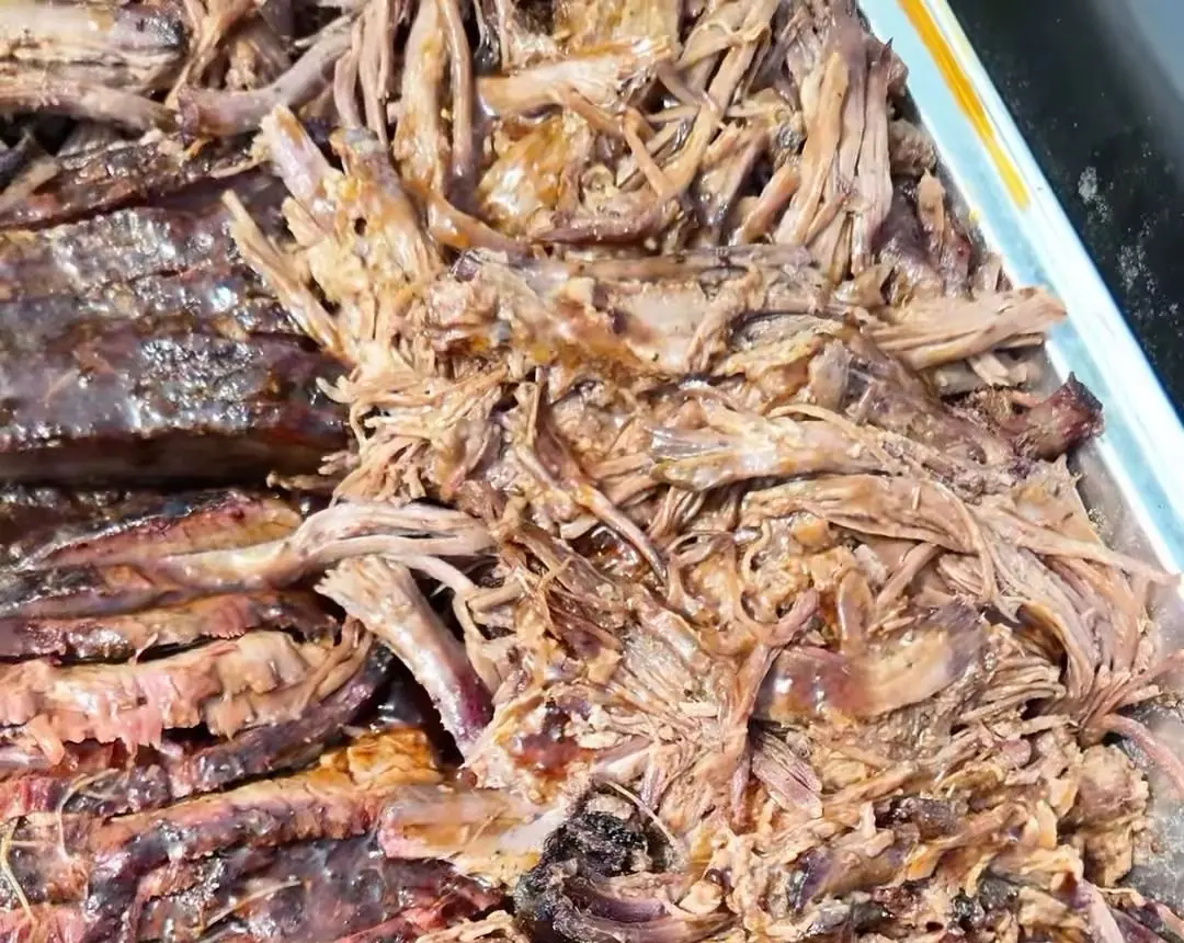 Smoked brisket close up: dark bark on the sliced side, tender pulled strands on the other
