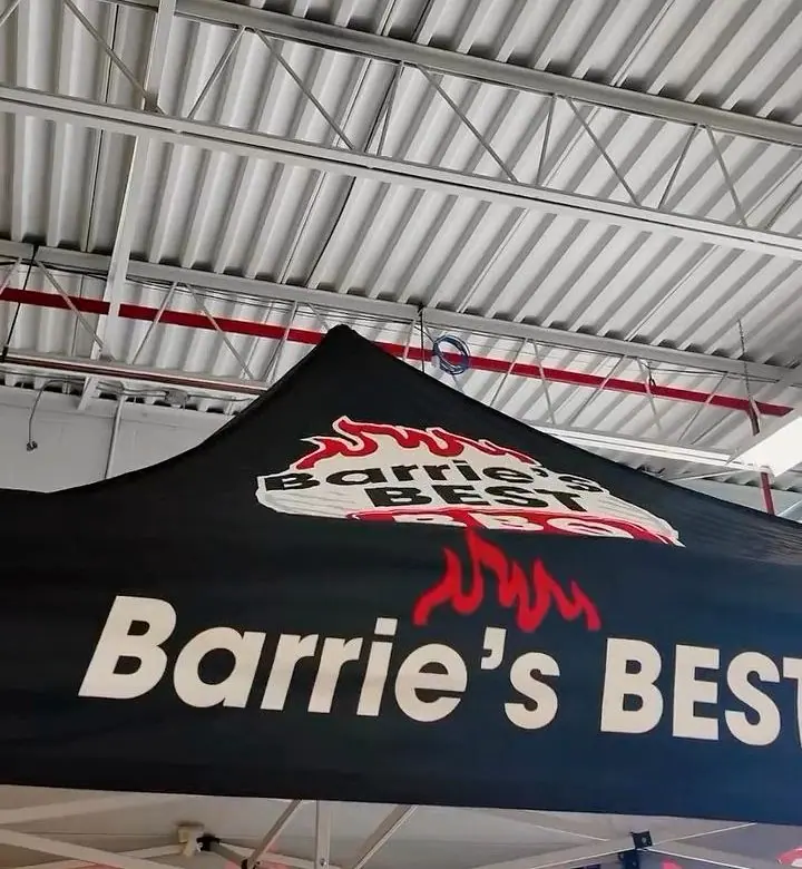 The black Barrie’s Best BBQ pop-up tent with its flame print, set up indoors at an event